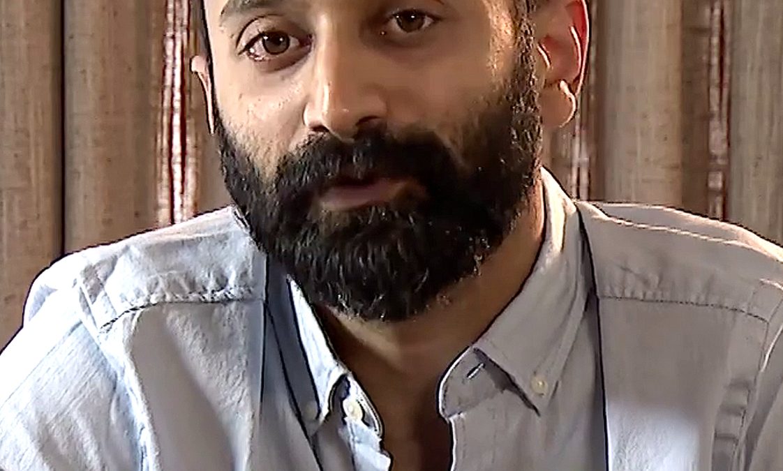 Fahadh Faasil with a beard, in a light shirt, gesturing with both hands as he talks