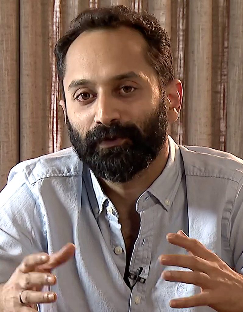 Fahadh Faasil with a beard, in a light shirt, gesturing with both hands as he talks