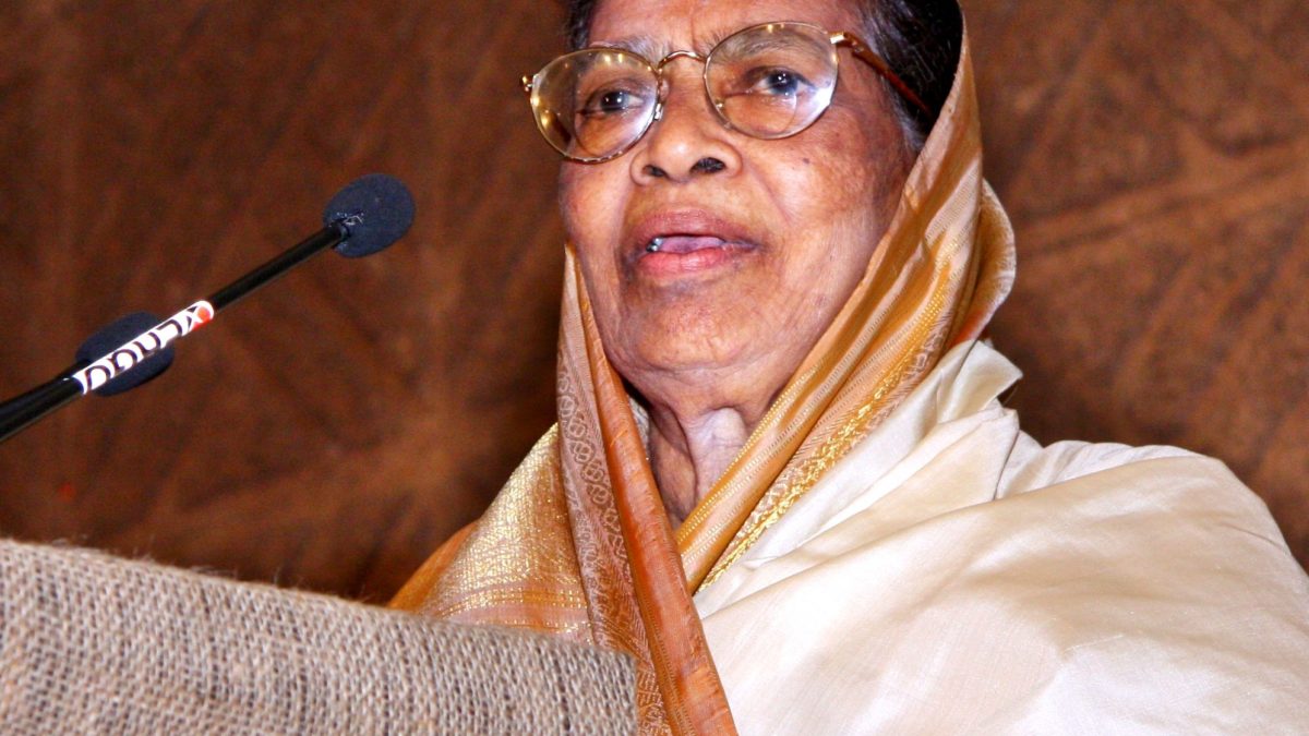 Fathima Beevi in glasses and a white headscarf speaking at a lectern