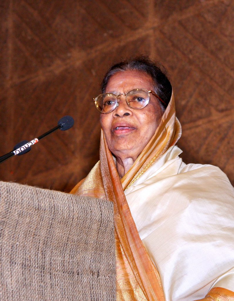 Fathima Beevi in glasses and a white headscarf speaking at a lectern