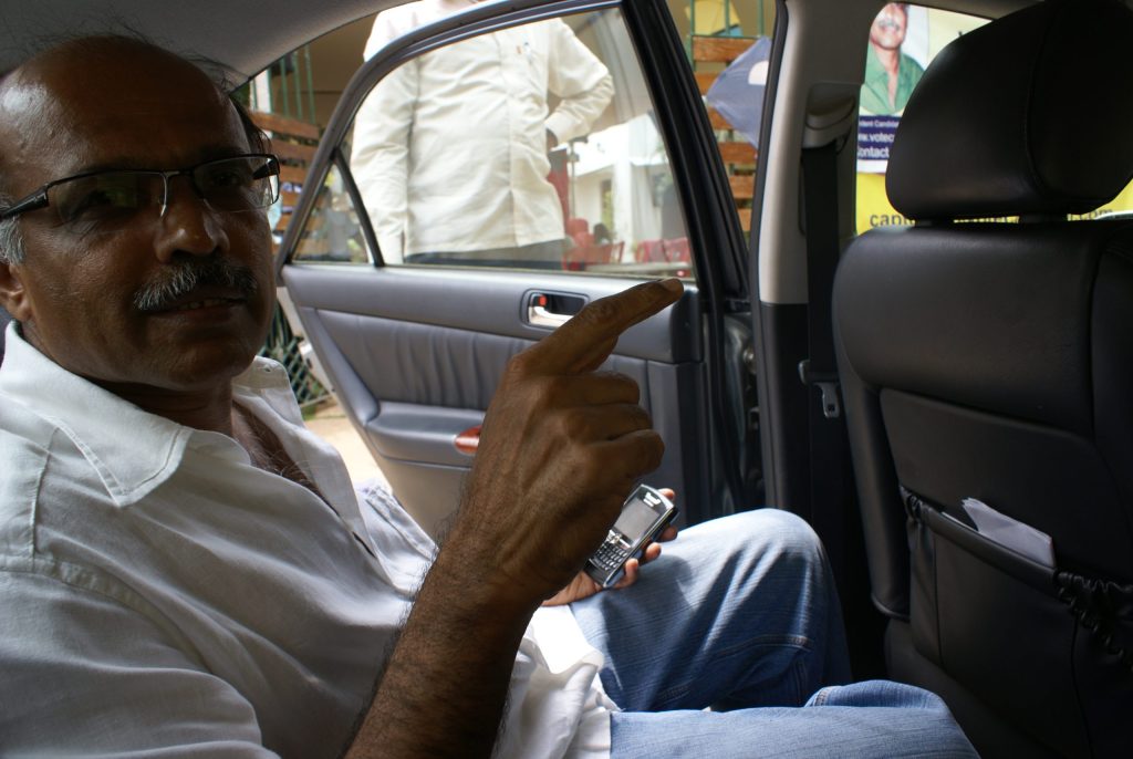Captain G. R. Gopinath seated in a car, in glasses and a white shirt
