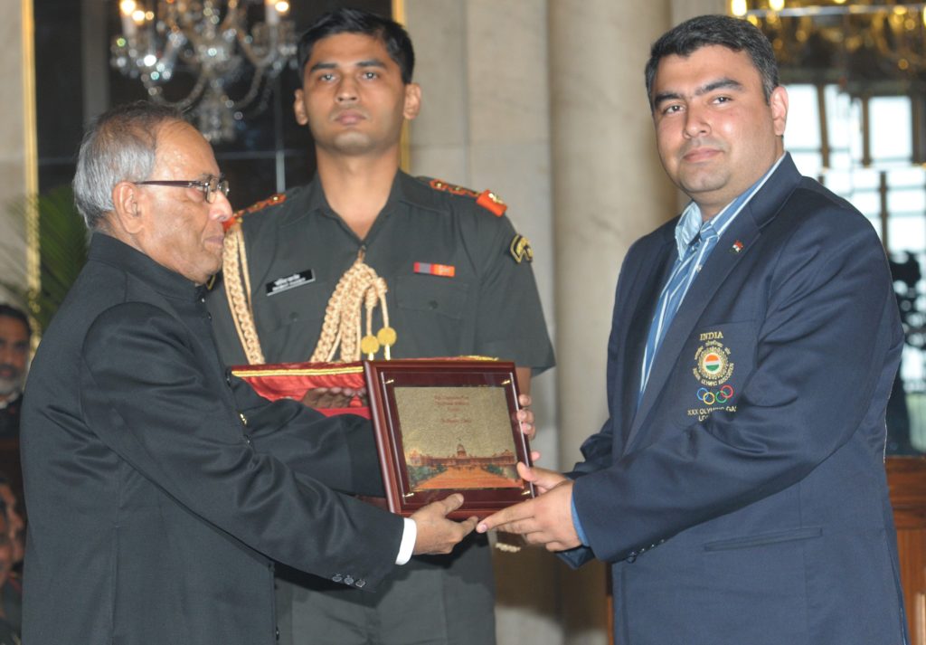 Gagan Narang in a navy blazer receiving a memento from President Pranab Mukherjee