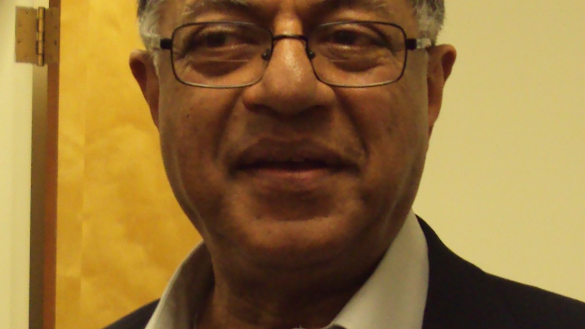 Girish Karnad in glasses, a dark jacket and open-collared shirt, smiling