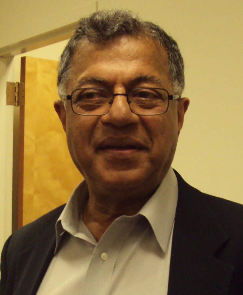 Girish Karnad in glasses, a dark jacket and open-collared shirt, smiling