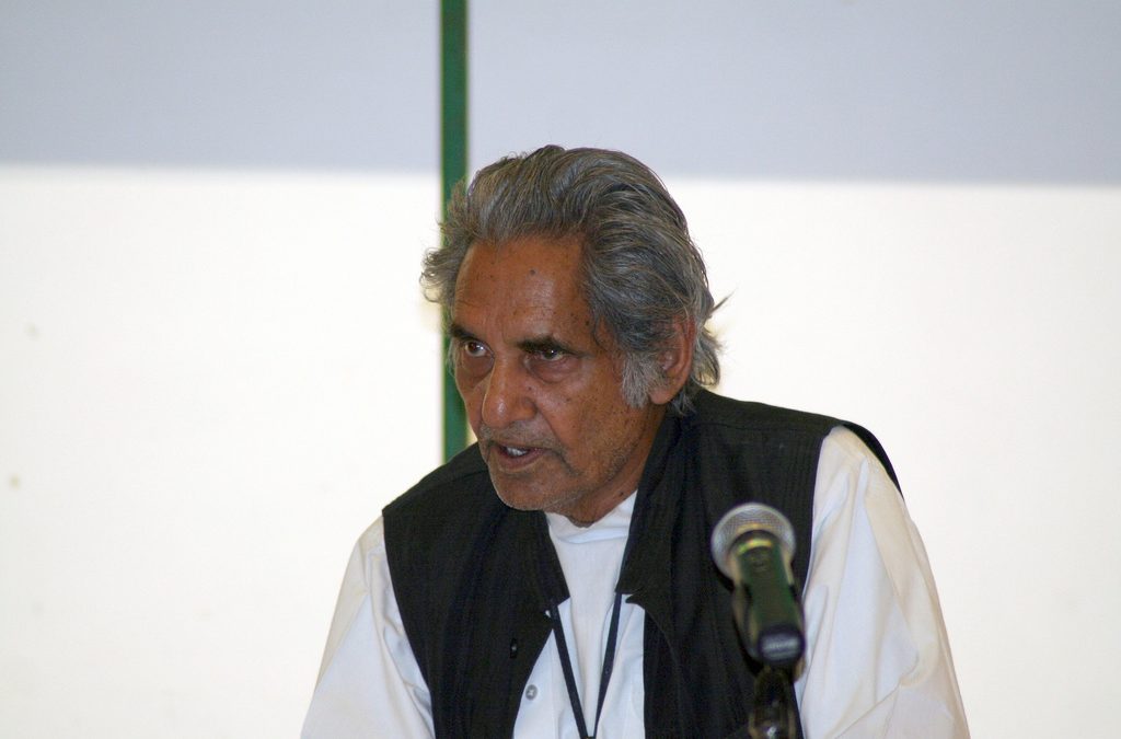 Gopaldas Neeraj with grey hair, in a dark waistcoat, speaking into a microphone