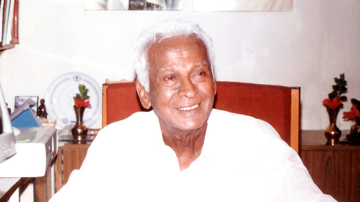 Dr Govindappa Venkataswamy smiling at his desk, in white