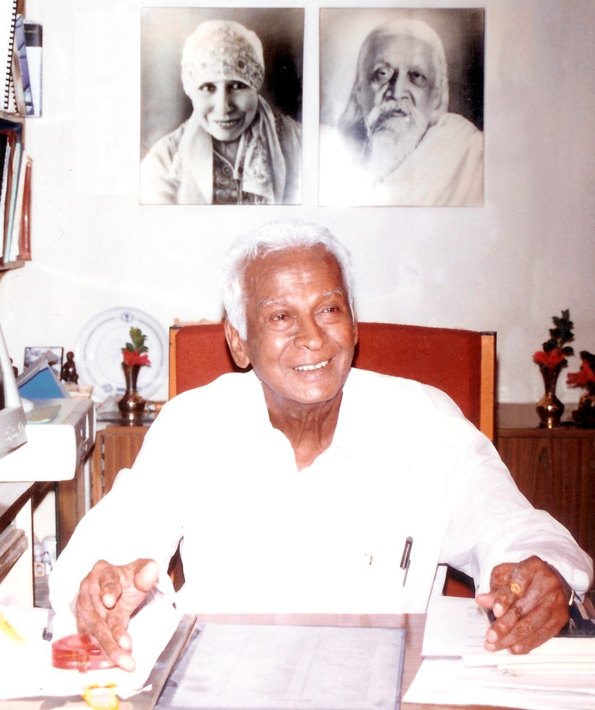 Dr Govindappa Venkataswamy smiling at his desk, in white