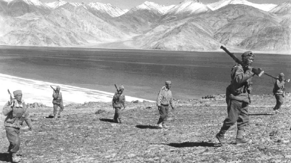 A black-and-white photograph of Indian soldiers on patrol beside a lake in the mountains during the 1962 border war
