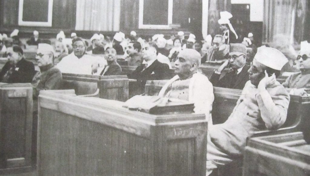A black-and-white photograph of members seated at desks in the Constituent Assembly of India in December 1946