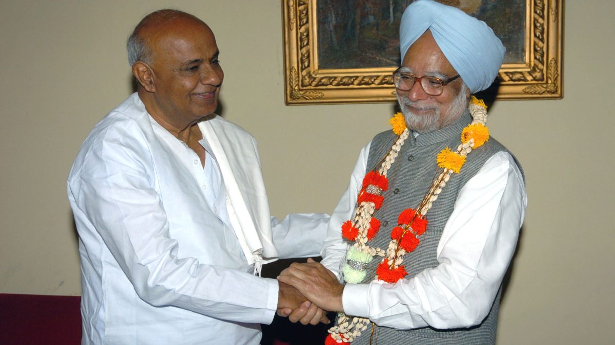 H. D. Deve Gowda in white garlanding and shaking hands with Prime Minister Manmohan Singh