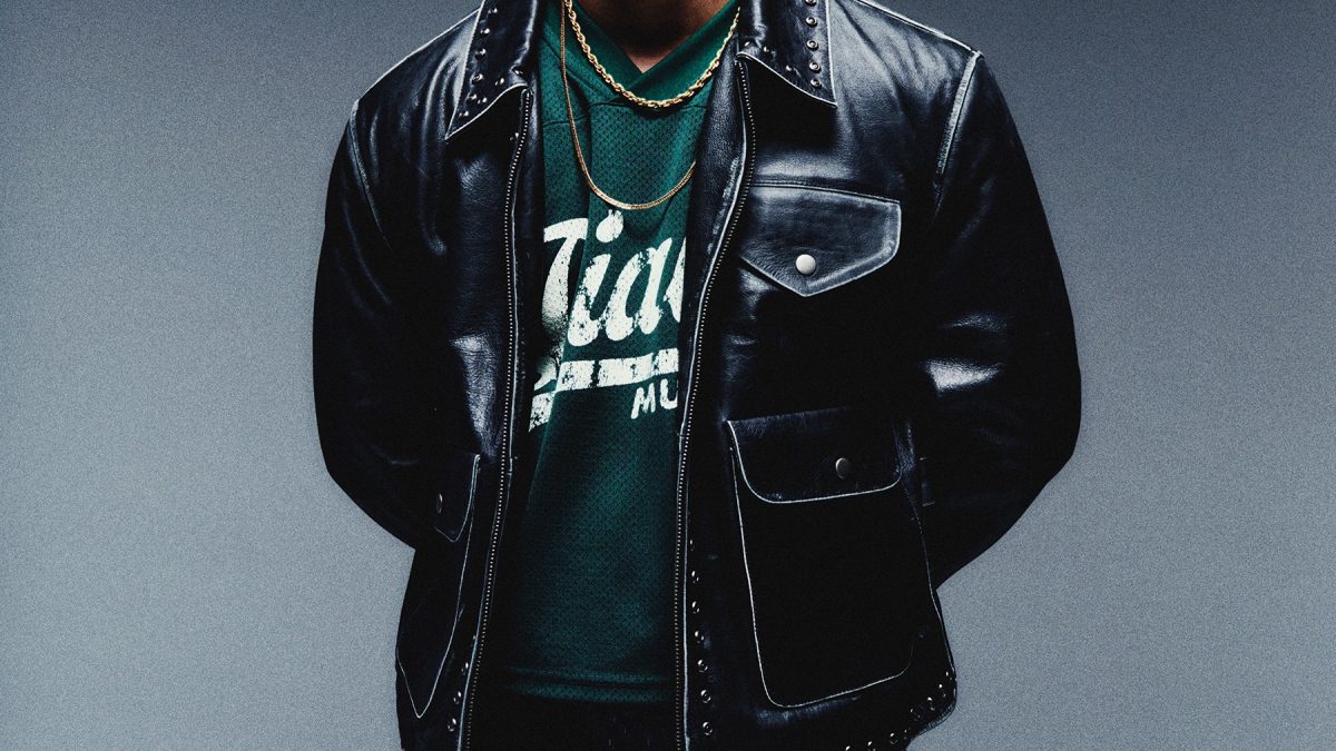 Hanumankind with curly hair in a black leather jacket, head tilted back