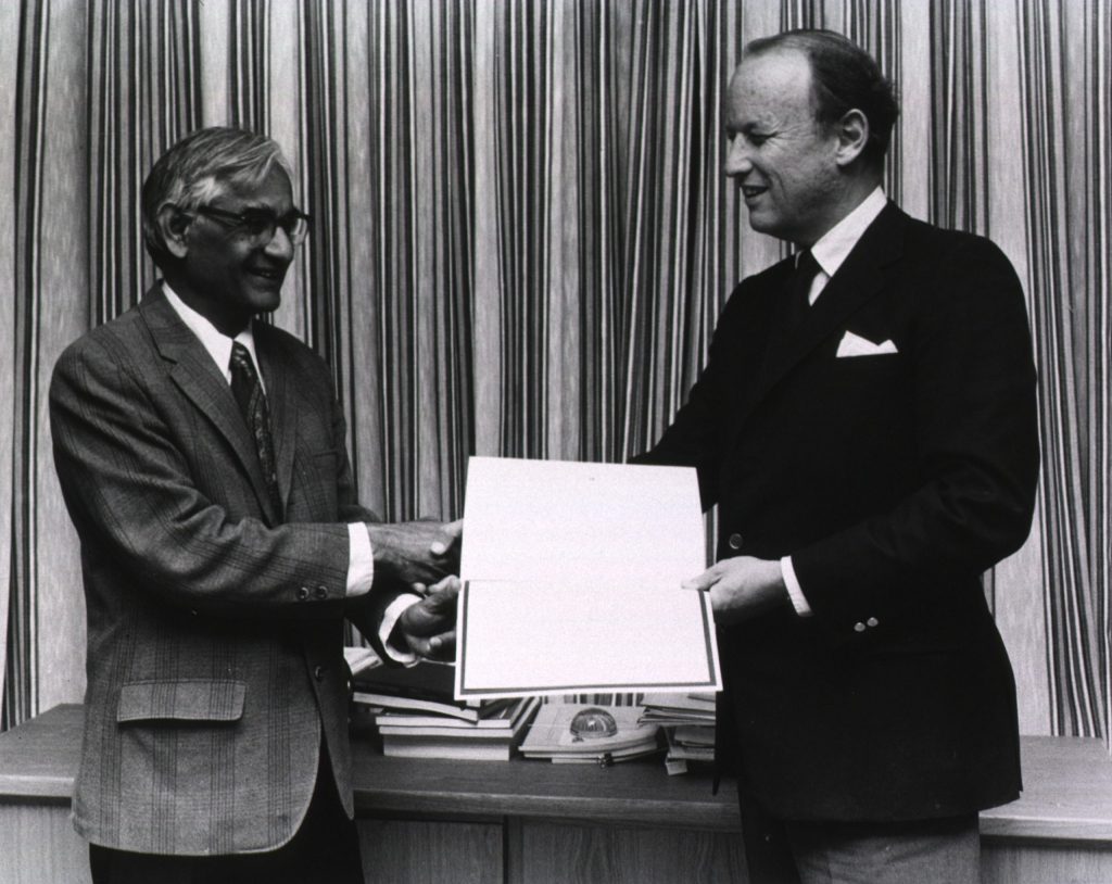 Har Gobind Khorana in a dark suit and glasses receiving a certificate from another man