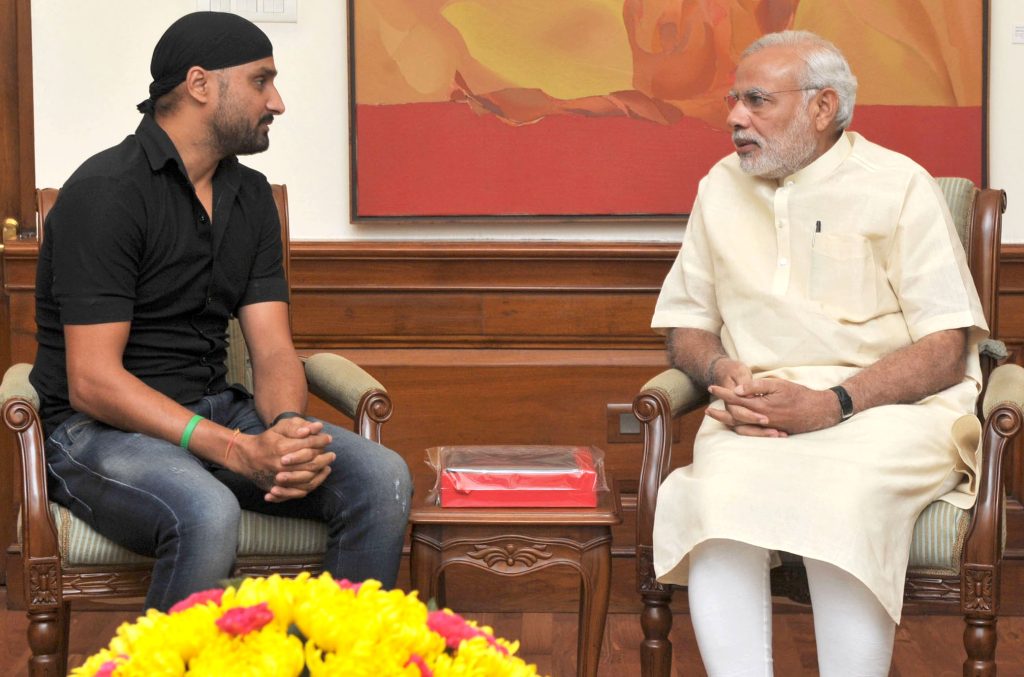 Harbhajan Singh in a black turban and T-shirt seated in conversation with Prime Minister Narendra Modi