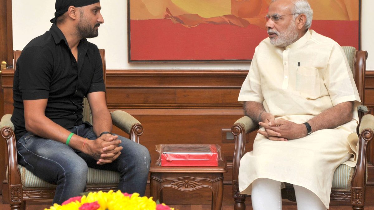 Harbhajan Singh in a black turban and T-shirt seated in conversation with Prime Minister Narendra Modi