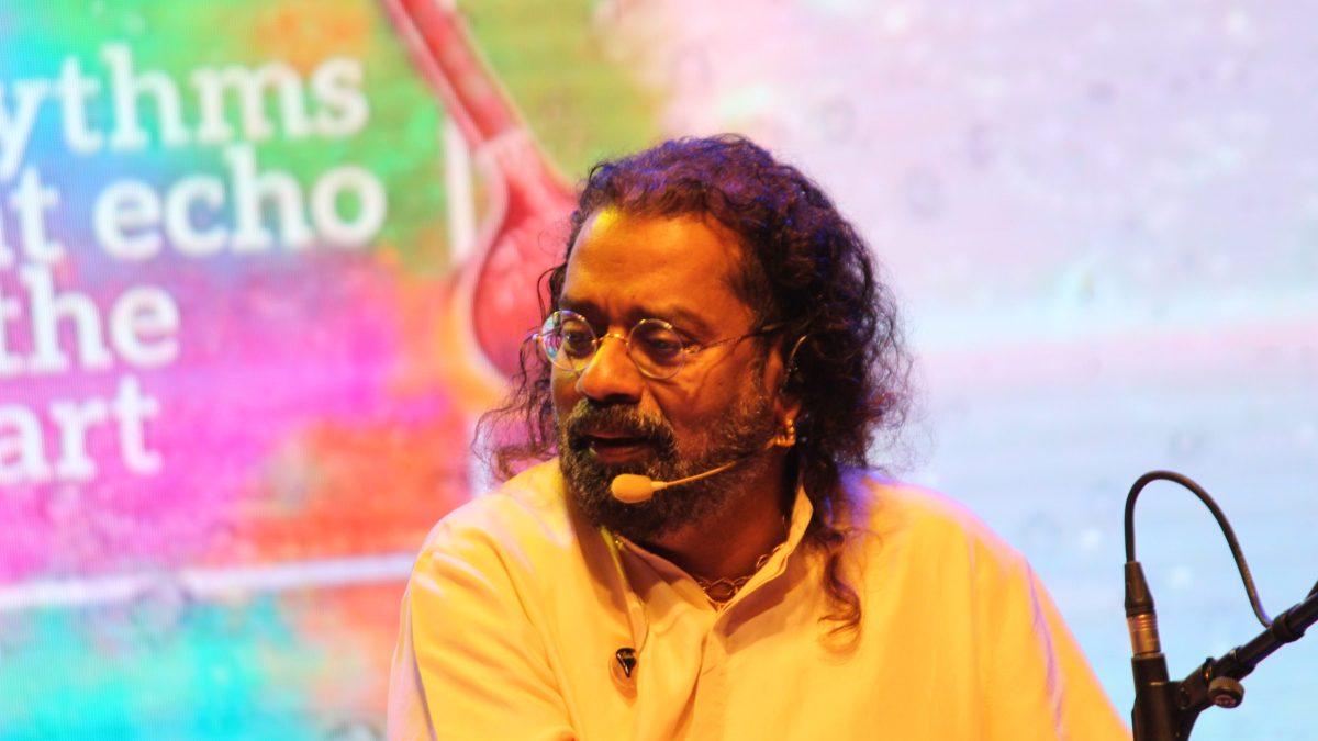 Hariharan with long curly hair and a headset microphone, wearing a yellow kurta