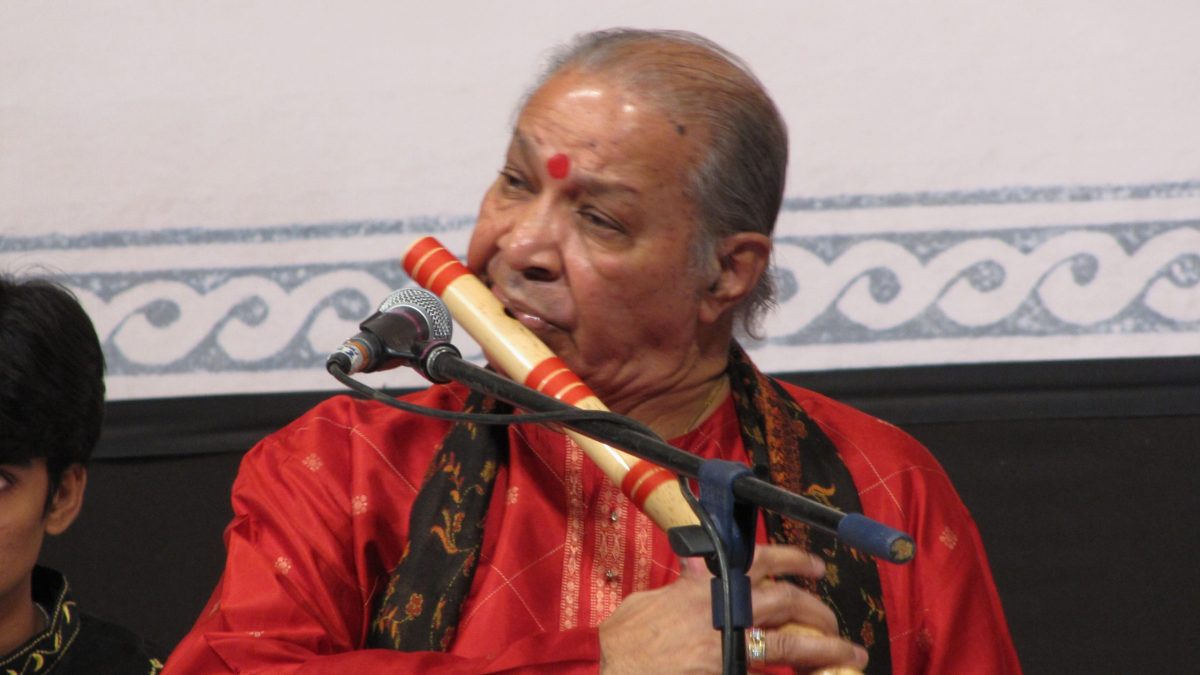 Hariprasad Chaurasia in a red kurta playing the bamboo flute on stage