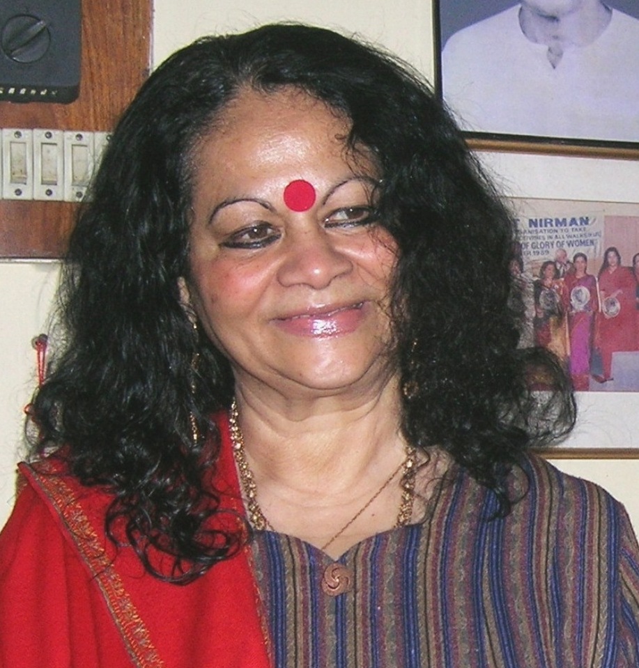 Indira Goswami with long curly hair and a large red bindi, smiling