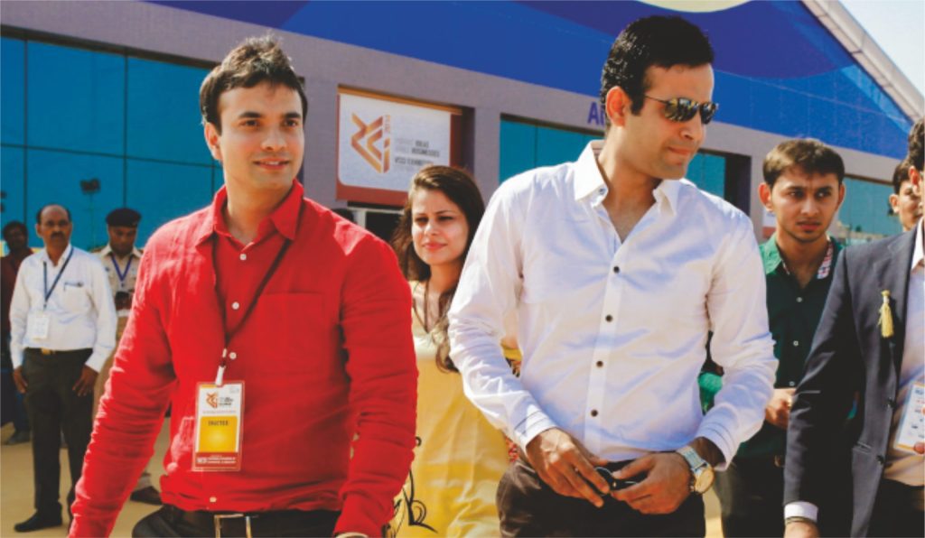 Irfan Pathan in a white shirt standing with a man in a red jacket at an event