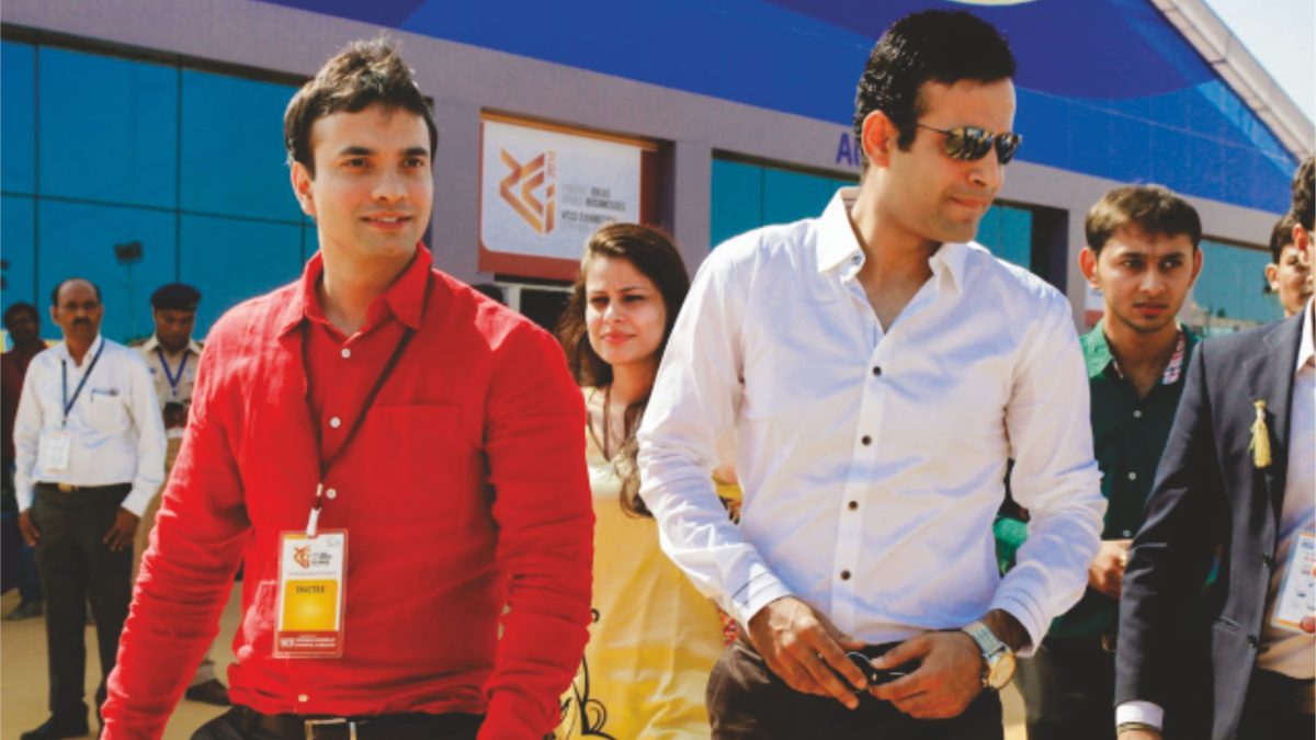 Irfan Pathan in a white shirt standing with a man in a red jacket at an event