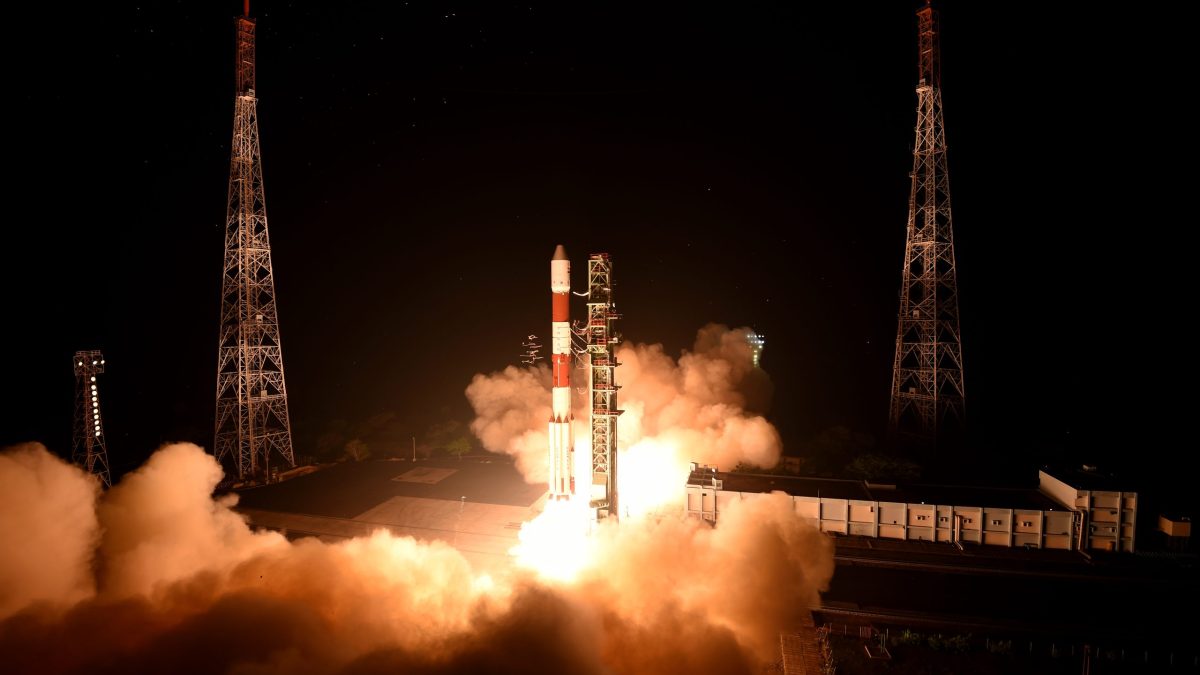 An ISRO PSLV rocket lifting off at night amid clouds of smoke
