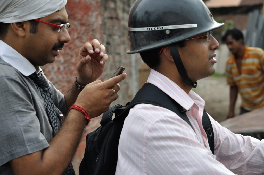 Motorcyclists using mobile phones on a road in Barrackpore