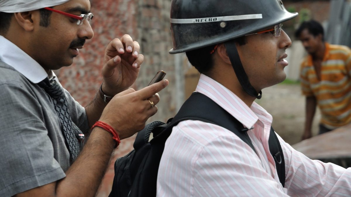 Motorcyclists using mobile phones on a road in Barrackpore