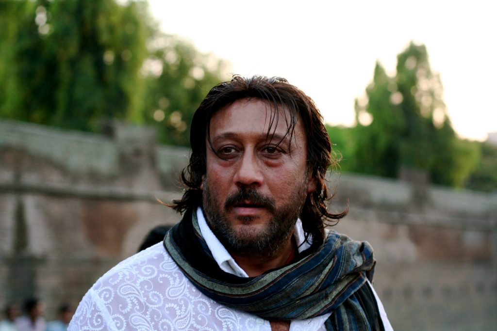 Jackie Shroff with a moustache and long hair, wearing a black scarf, outdoors