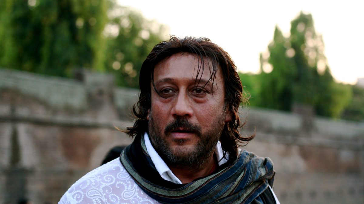 Jackie Shroff with a moustache and long hair, wearing a black scarf, outdoors