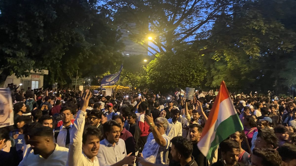 A large crowd of protesters, some holding the Indian flag, at night near Jantar Mantar in New Delhi