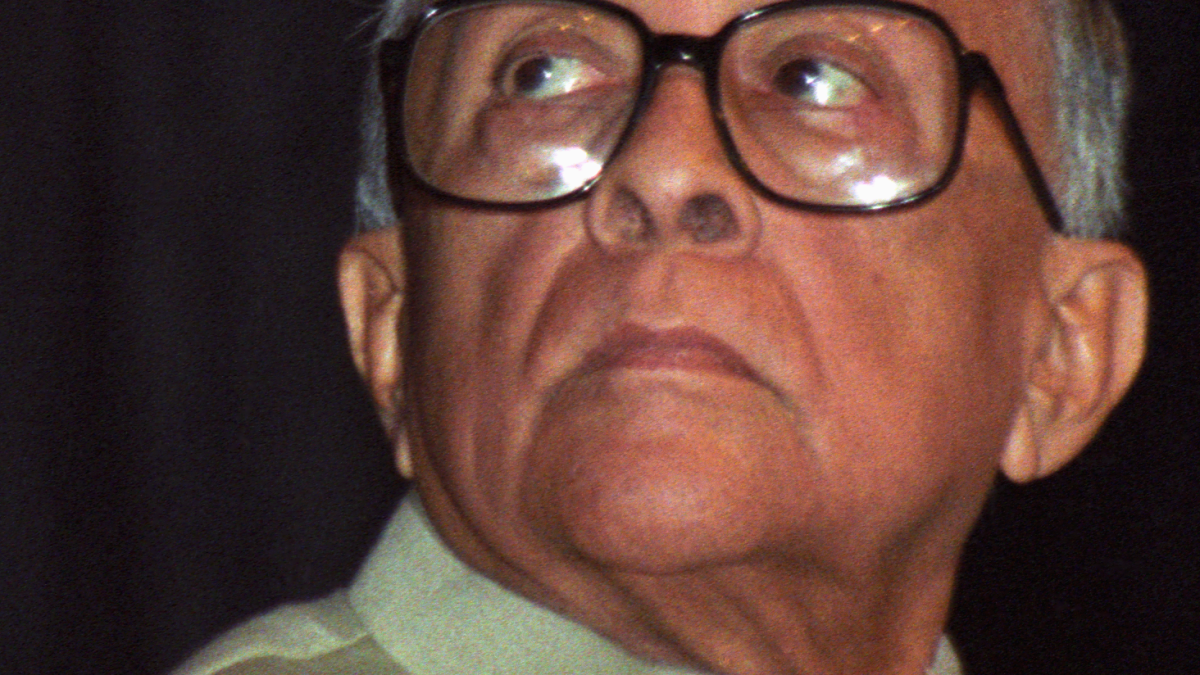 Jyoti Basu in large glasses and a cream waistcoat, looking upward