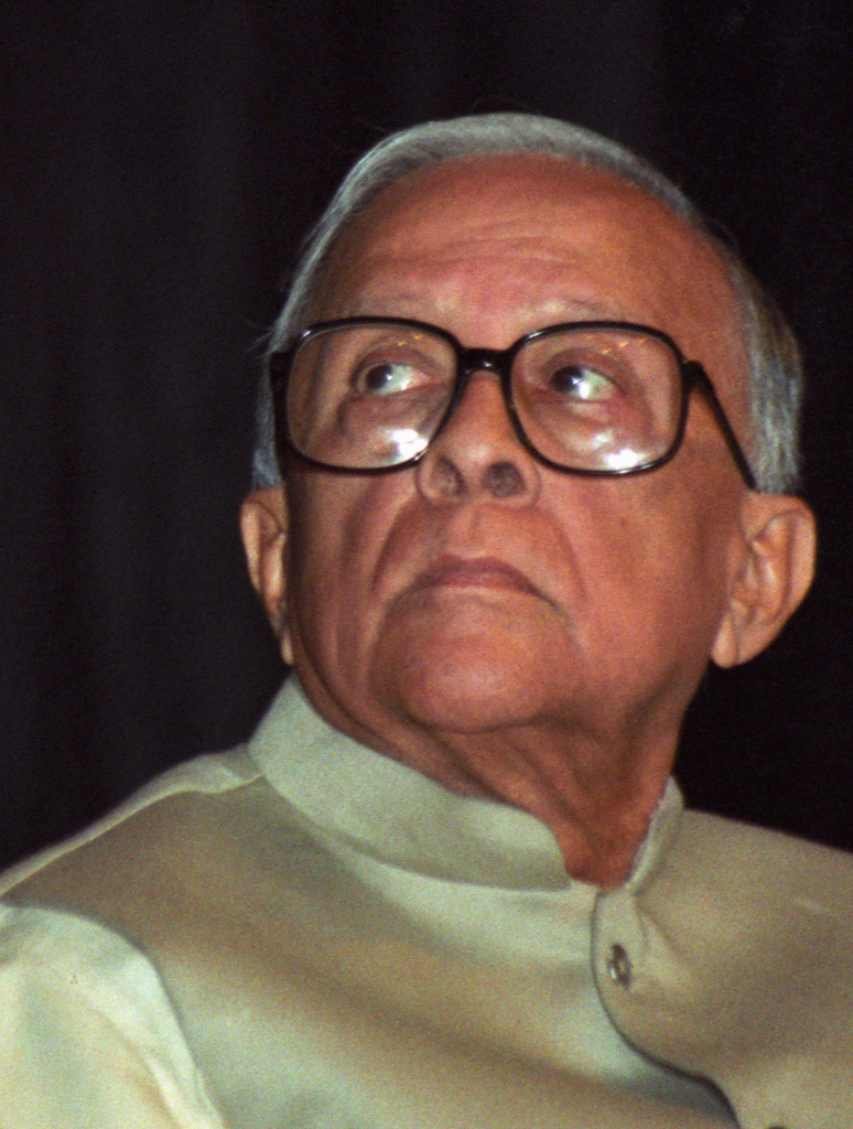 Jyoti Basu in large glasses and a cream waistcoat, looking upward