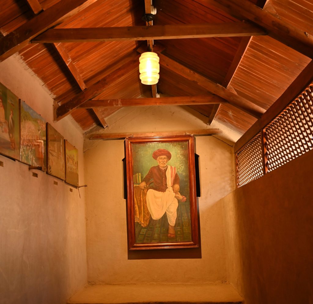 A framed painted portrait of Jyotirao Phule hanging in a wooden-roofed room