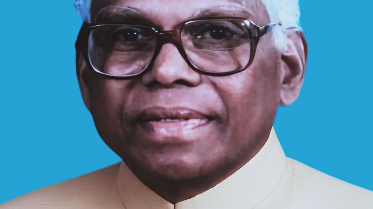 Official portrait of K. R. Narayanan in glasses and a white bandhgala against a blue background