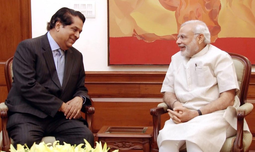 K. V. Kamath in a dark suit seated in conversation with Prime Minister Narendra Modi