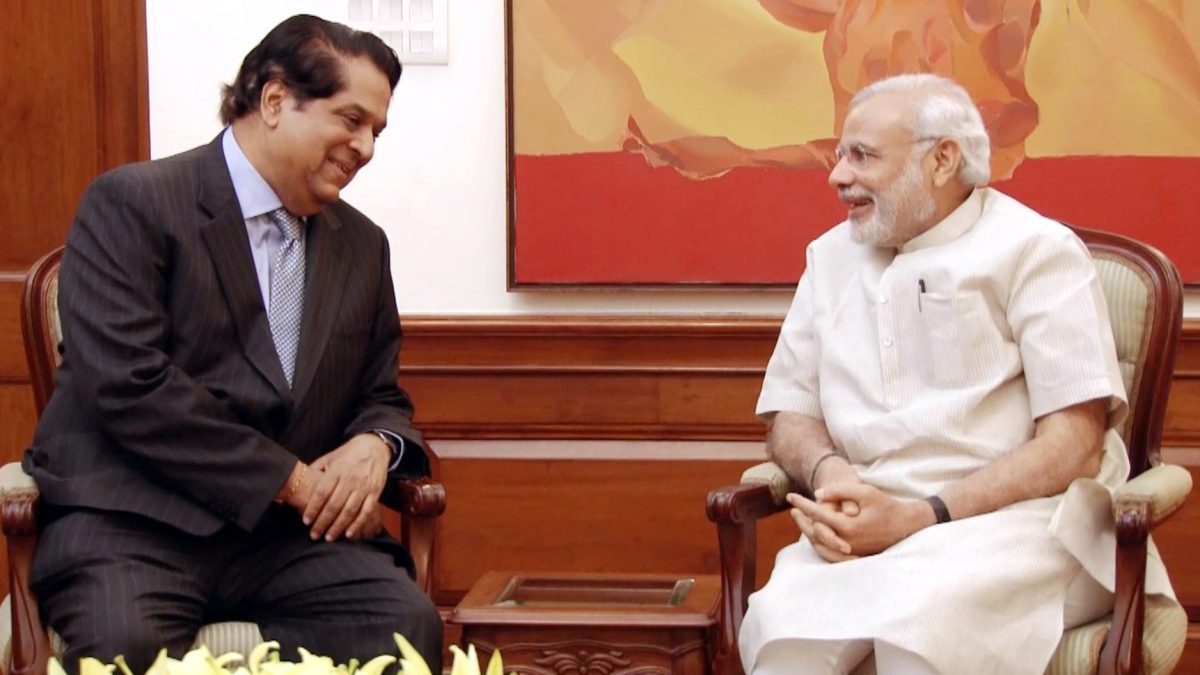 K. V. Kamath in a dark suit seated in conversation with Prime Minister Narendra Modi