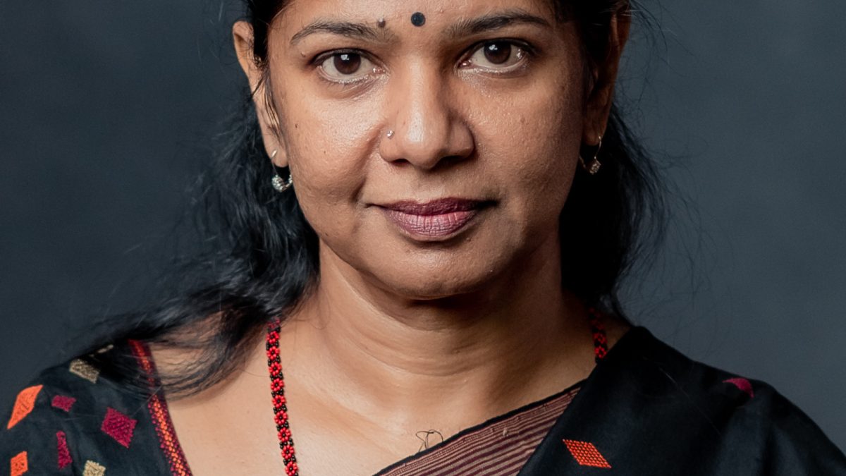 Portrait of Kanimozhi in a dark sari with a red bindi