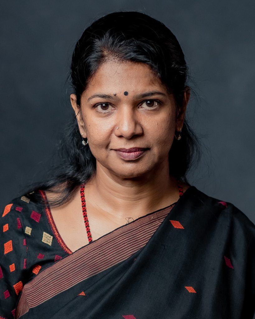 Portrait of Kanimozhi in a dark sari with a red bindi