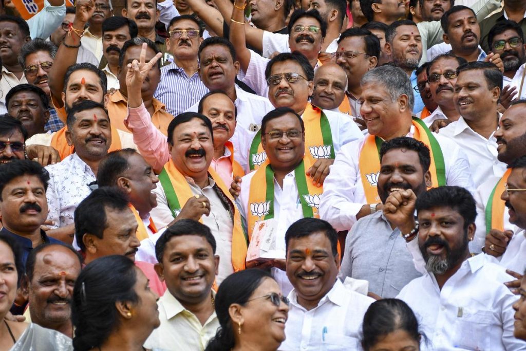 Smiling BJP supporters in saffron-and-green scarves celebrating together