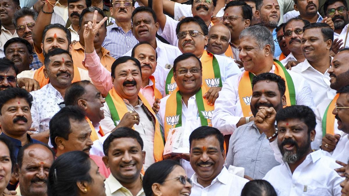Smiling BJP supporters in saffron-and-green scarves celebrating together