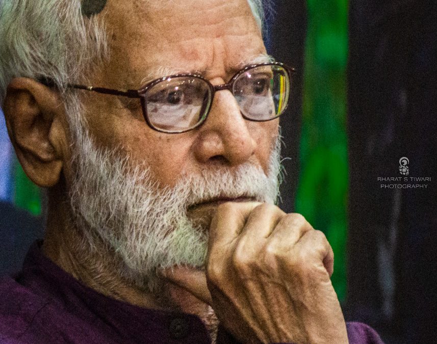 Kashinath Singh with a white beard and glasses, resting his chin on his hand