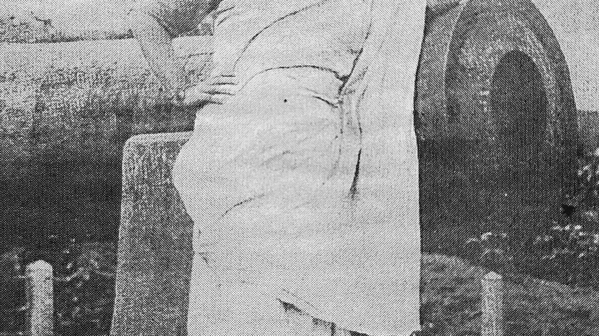 A young Kazi Nazrul Islam in a dhoti and shawl leaning against an old cannon