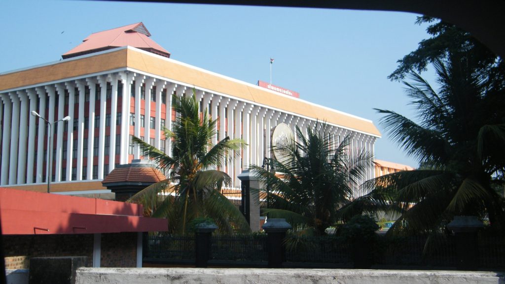 The Kerala Legislative Assembly building in Thiruvananthapuram seen through palm trees