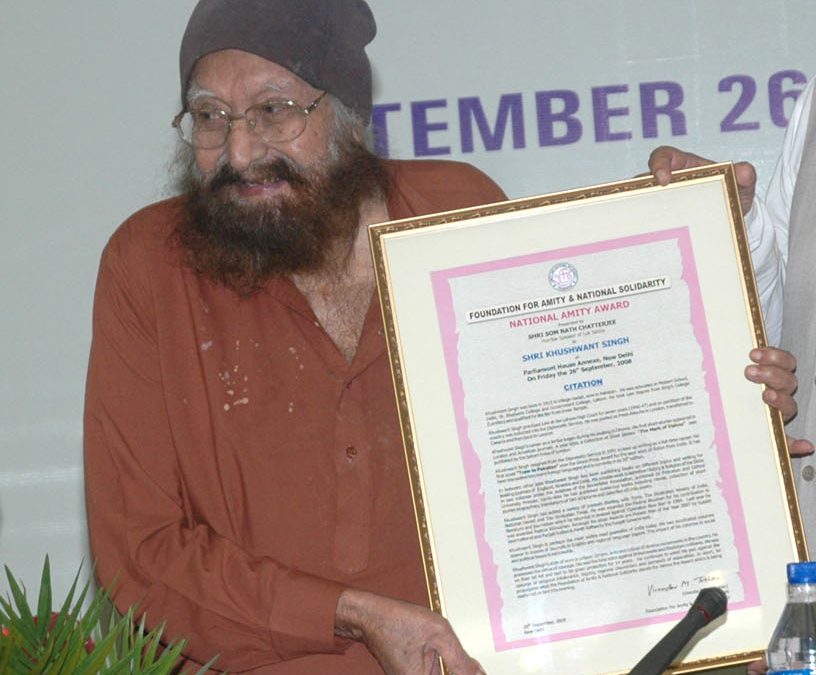 Khushwant Singh in a turban holding a framed citation