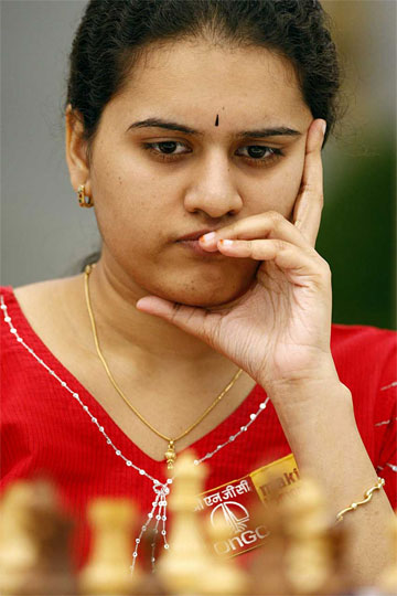 Koneru Humpy at a chessboard, chin resting on her hand