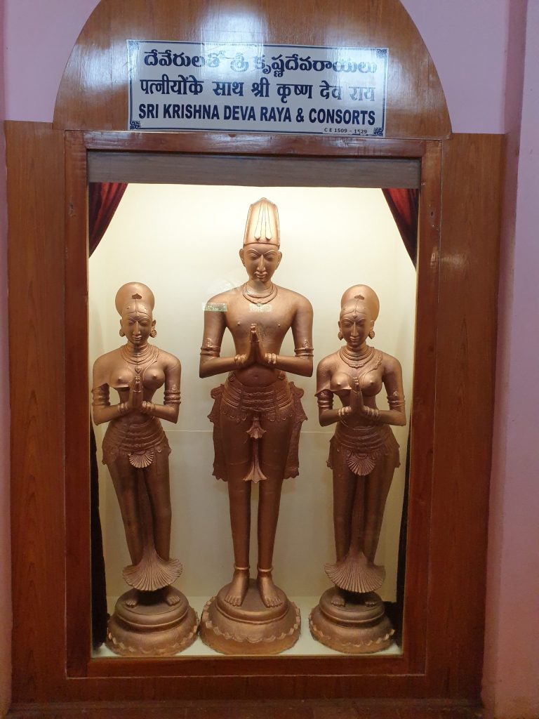 A framed photograph of the statues of Krishnadevaraya standing between his two queens