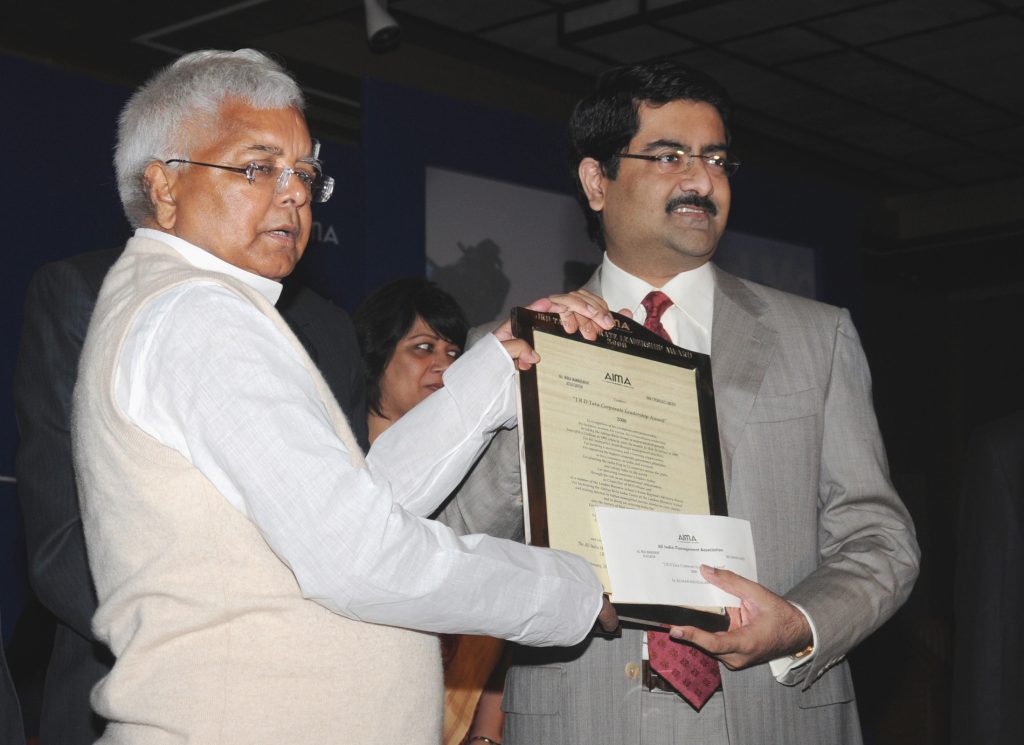 Kumar Mangalam Birla in a grey suit receiving an award from Lalu Prasad Yadav