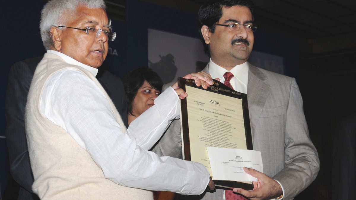 Kumar Mangalam Birla in a grey suit receiving an award from Lalu Prasad Yadav