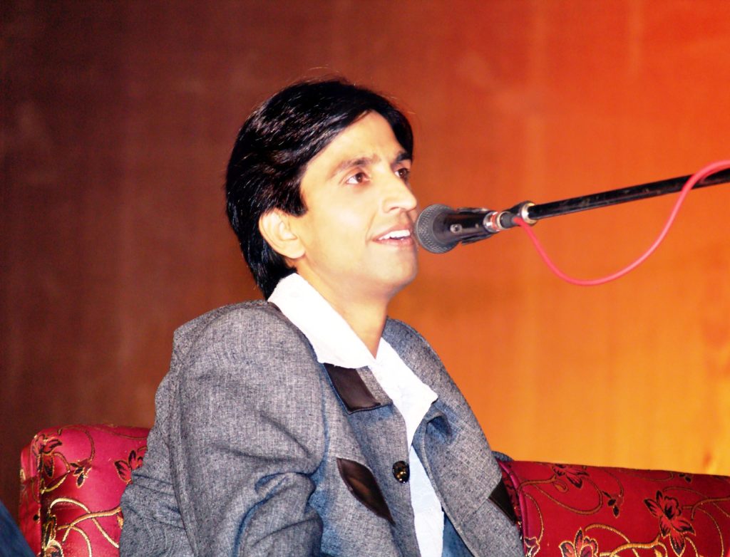 Kumar Vishwas in a grey jacket reciting poetry into a microphone