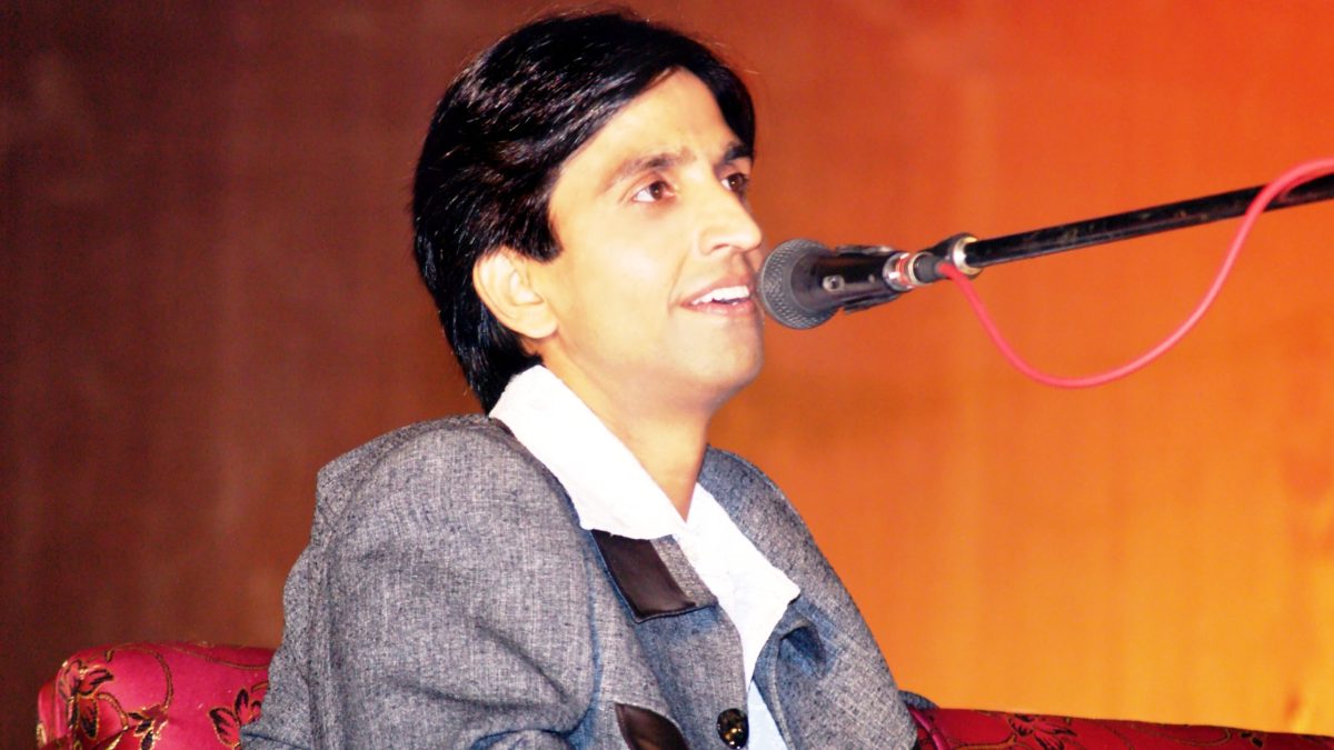 Kumar Vishwas in a grey jacket reciting poetry into a microphone