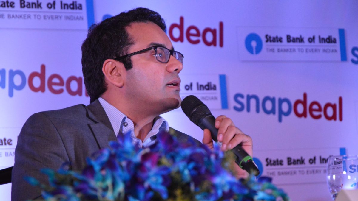 Kunal Bahl in glasses and a grey jacket speaking into a microphone at a Snapdeal event